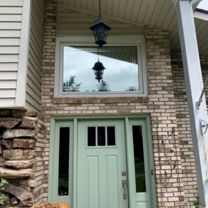 A brick home with a tinted window and tinted glass panes in the door.